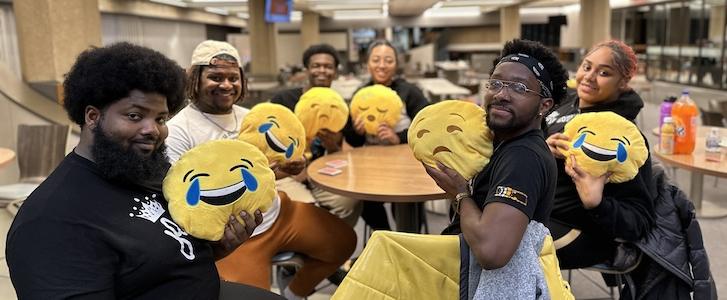 Six students holding emoji pillows